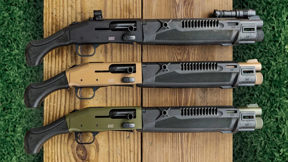 Three Mossberg 990 AfterShock SPX 14.75 in. shotguns in black, Flat Dark Earth and OD Green on a wooden bench, the black one fitted with a red dot and a weapon light
