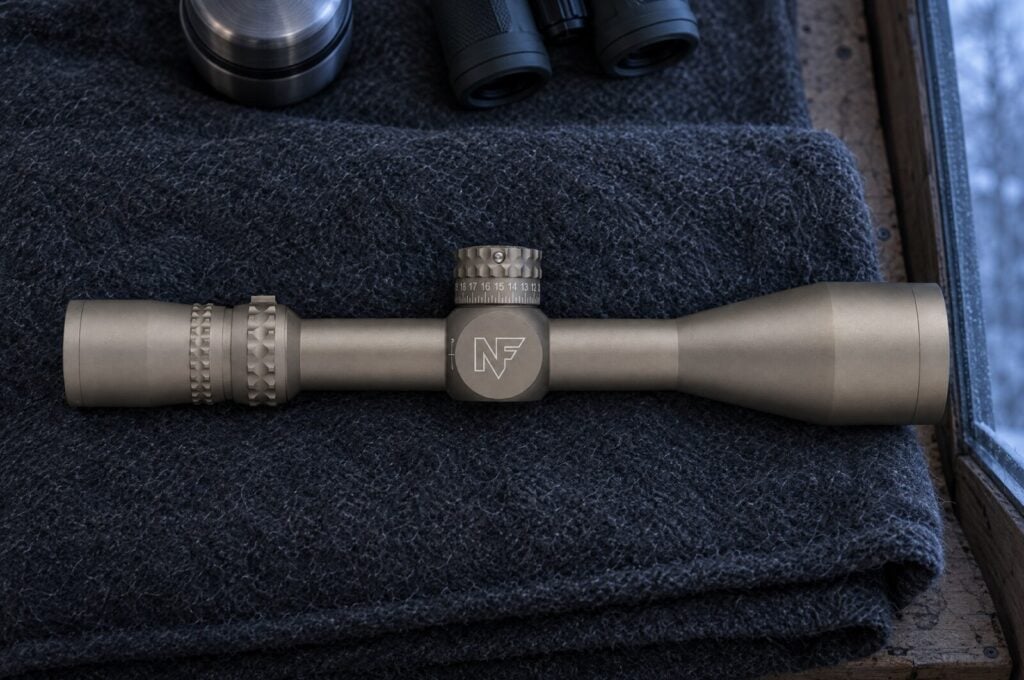 Dark Earth Nightforce NX8 4-32 power first focal plane rifle scope on a gray wool blanket in a hunting blind at dawn