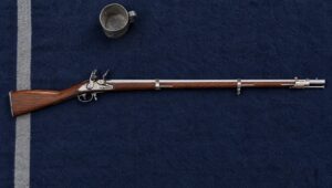 Muskets: a Pedersoli 1816 Harpers Ferry flintlock musket lying flat on a navy blue wool army blanket beside a tin cup