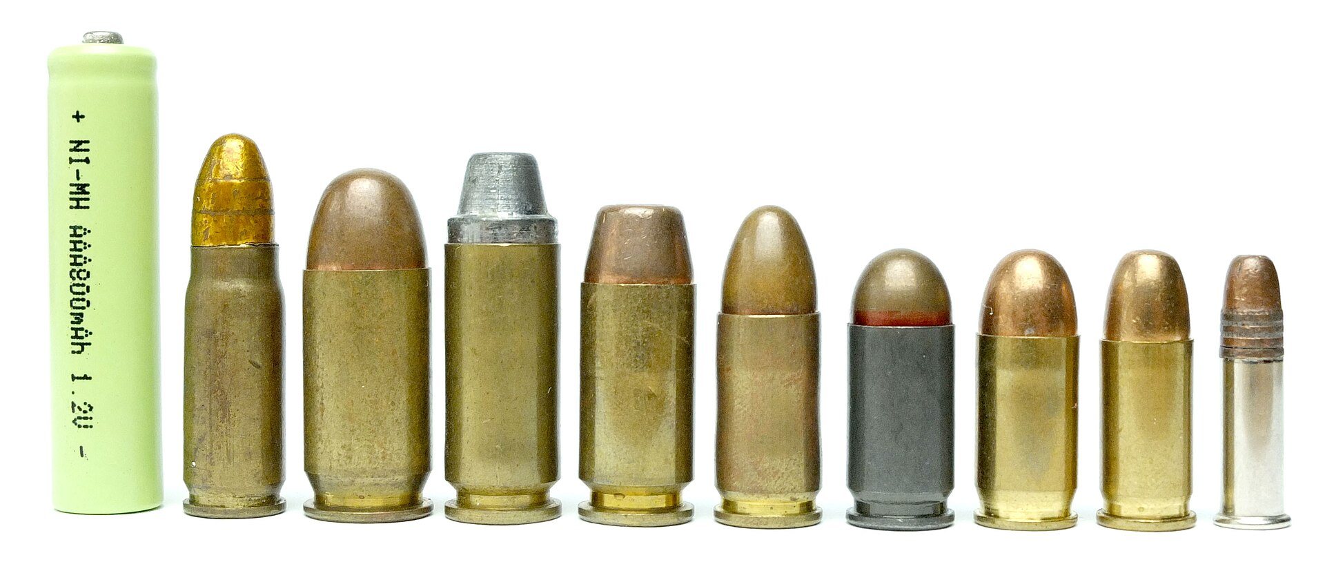 Nine pistol cartridges in a row, including 9x18 Makarov, beside an AAA cell