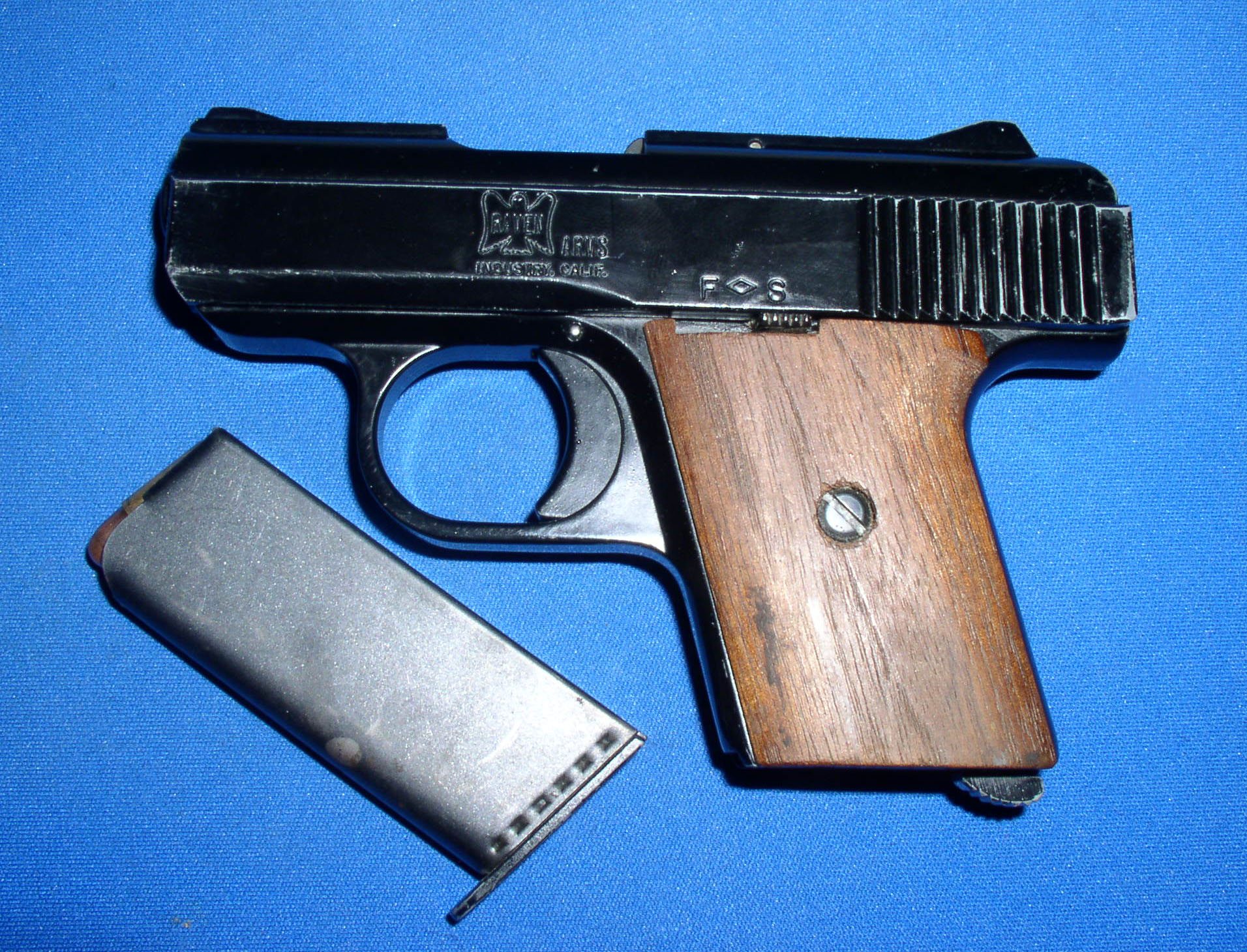 Raven Arms MP-25 pistol with wood grips and its magazine on blue cloth