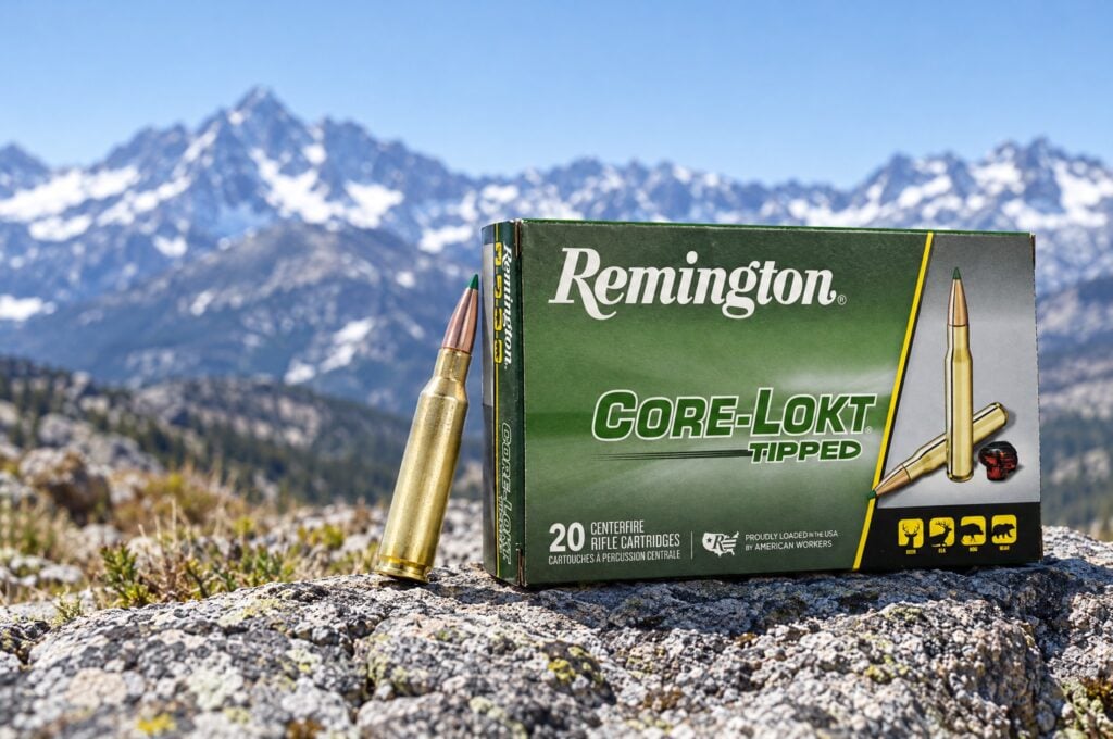 Remington Core-Lokt Tipped 6.5 Creedmoor 129 grain box and green tipped cartridge on granite below snowy peaks