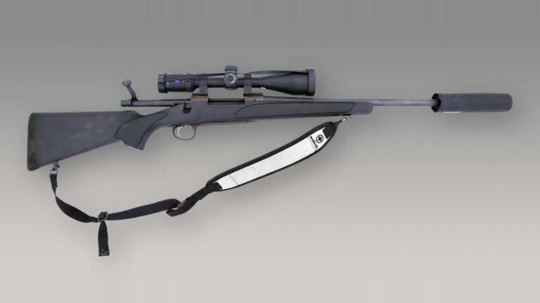 Remington Model 700 bolt-action rifle with a synthetic stock, scope, sling and suppressor on a gray background