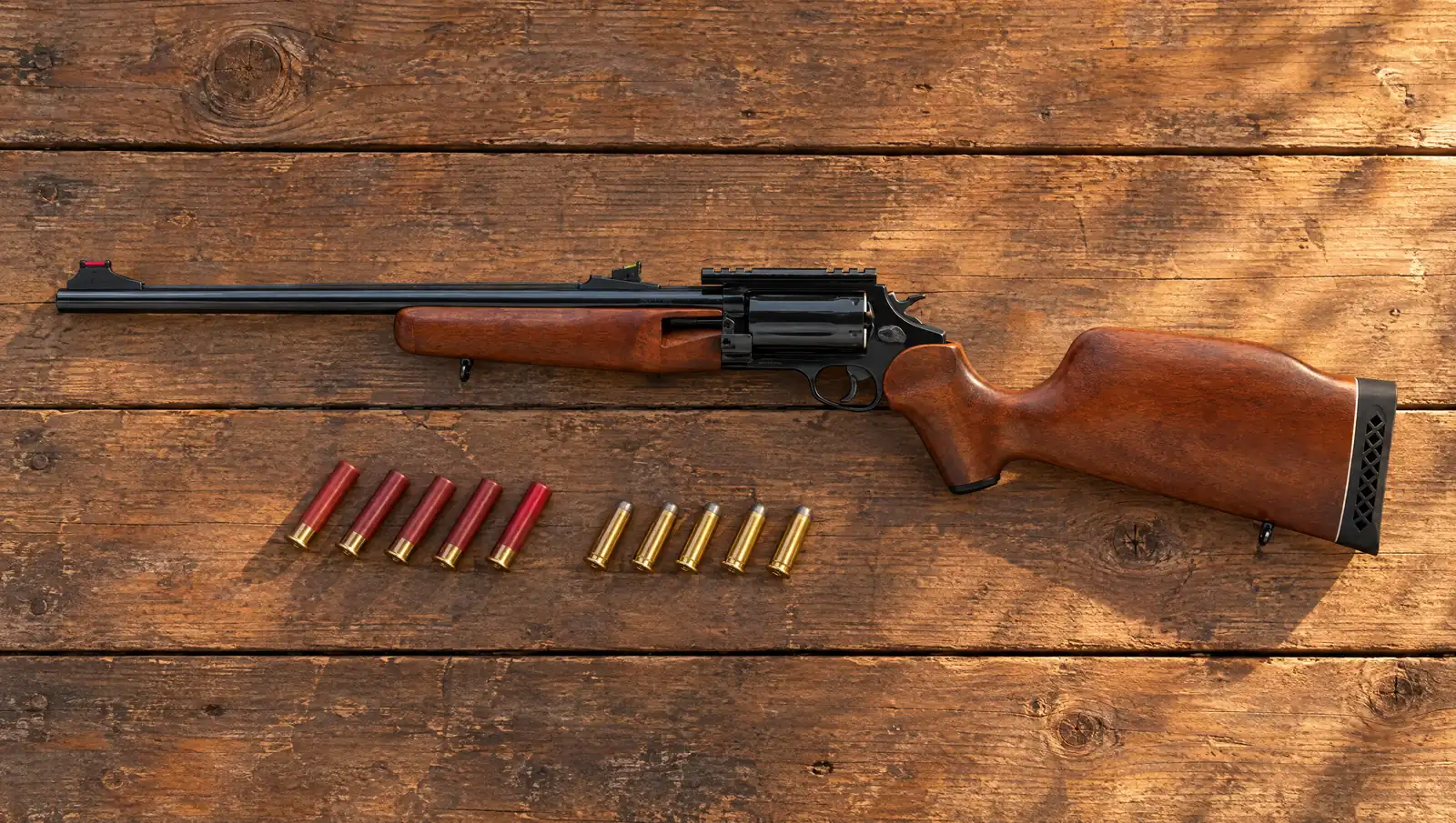 Rossi Circuit Judge SCJ4510 revolving rifle with a hardwood stock and polished black barrel and cylinder, lying on a wooden tailgate beside five .410 shells and five .45 Colt cartridges