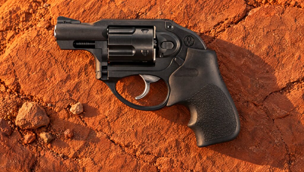Black Ruger LCR revolver lying on red desert sandstone at sunset