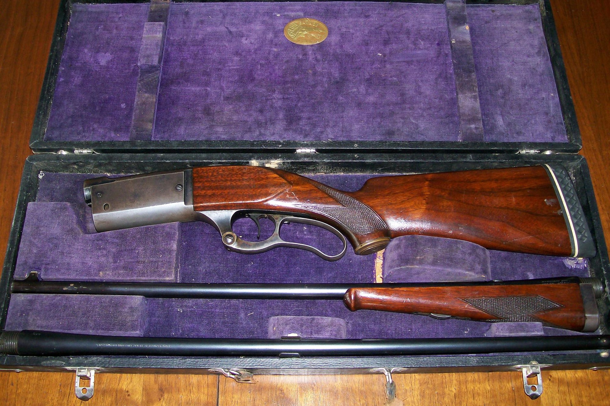 Cased takedown Savage Model 99 lever-action rifle with spare barrel and Indian-head label in a purple velvet case