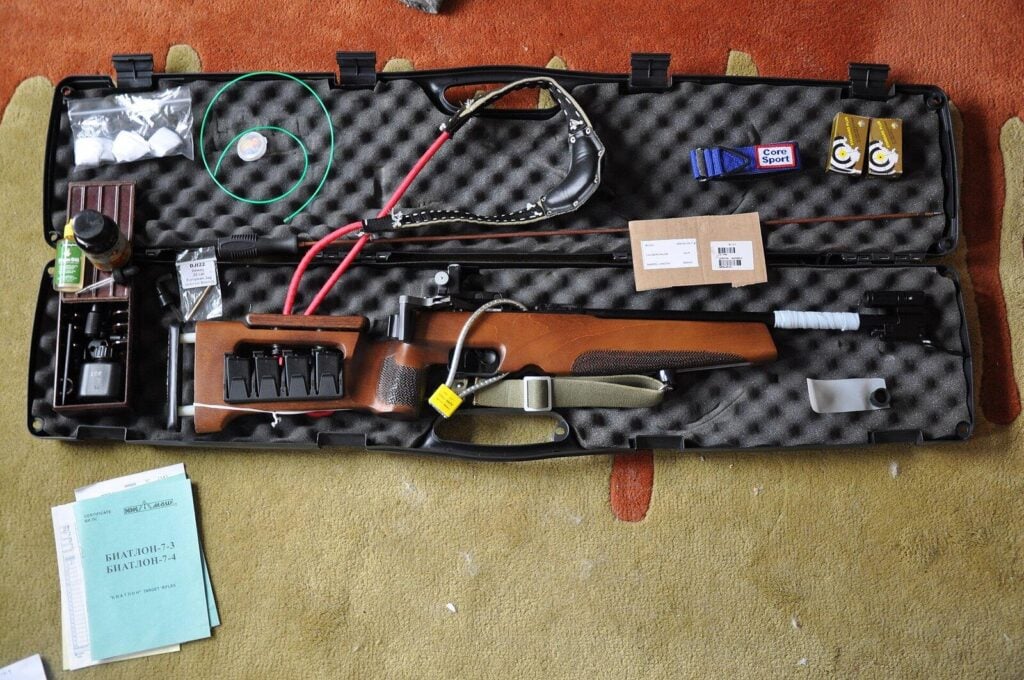 Rifle locked in an open hard gun case with a cable lock, alongside its manual and certificate