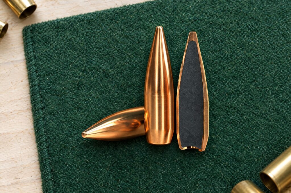 Sellier & Bellot FMJ rifle bullets, one sectioned to show the lead core, on a green shooting mat