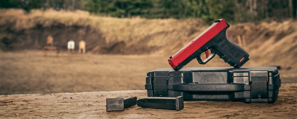 Red SIRT laser training pistol on a hard case on an outdoor range bench
