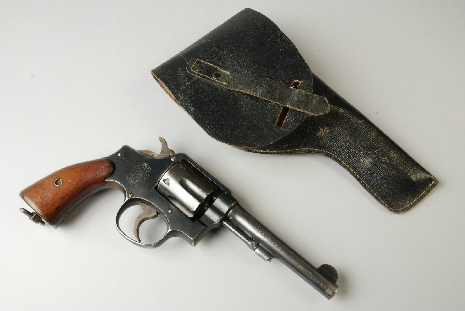 Smith and Wesson .38 Military and Police revolver with lanyard ring next to a black leather police holster