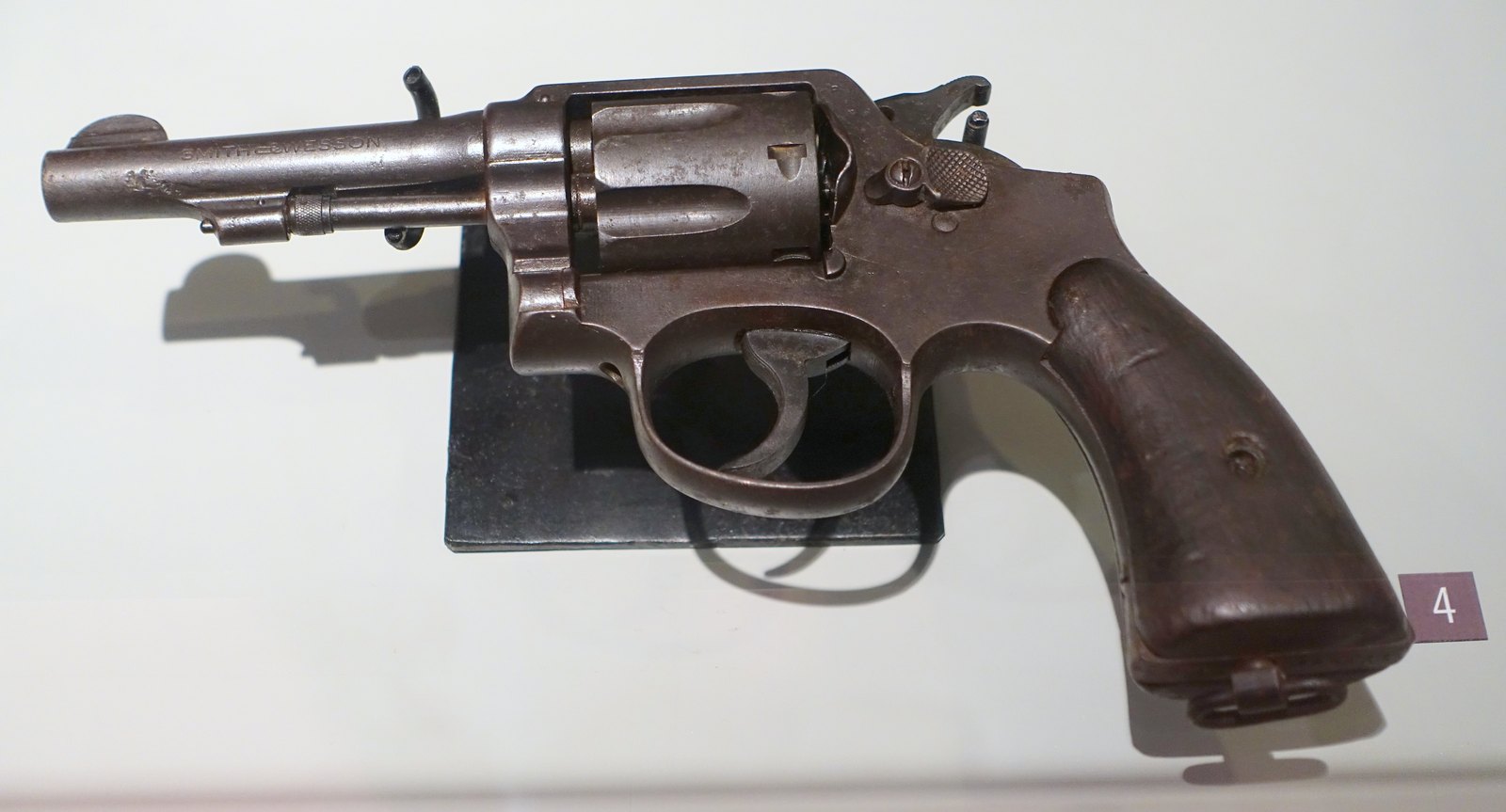 Heavily rusted and pitted Smith and Wesson Military and Police revolver with a lanyard ring on a museum stand