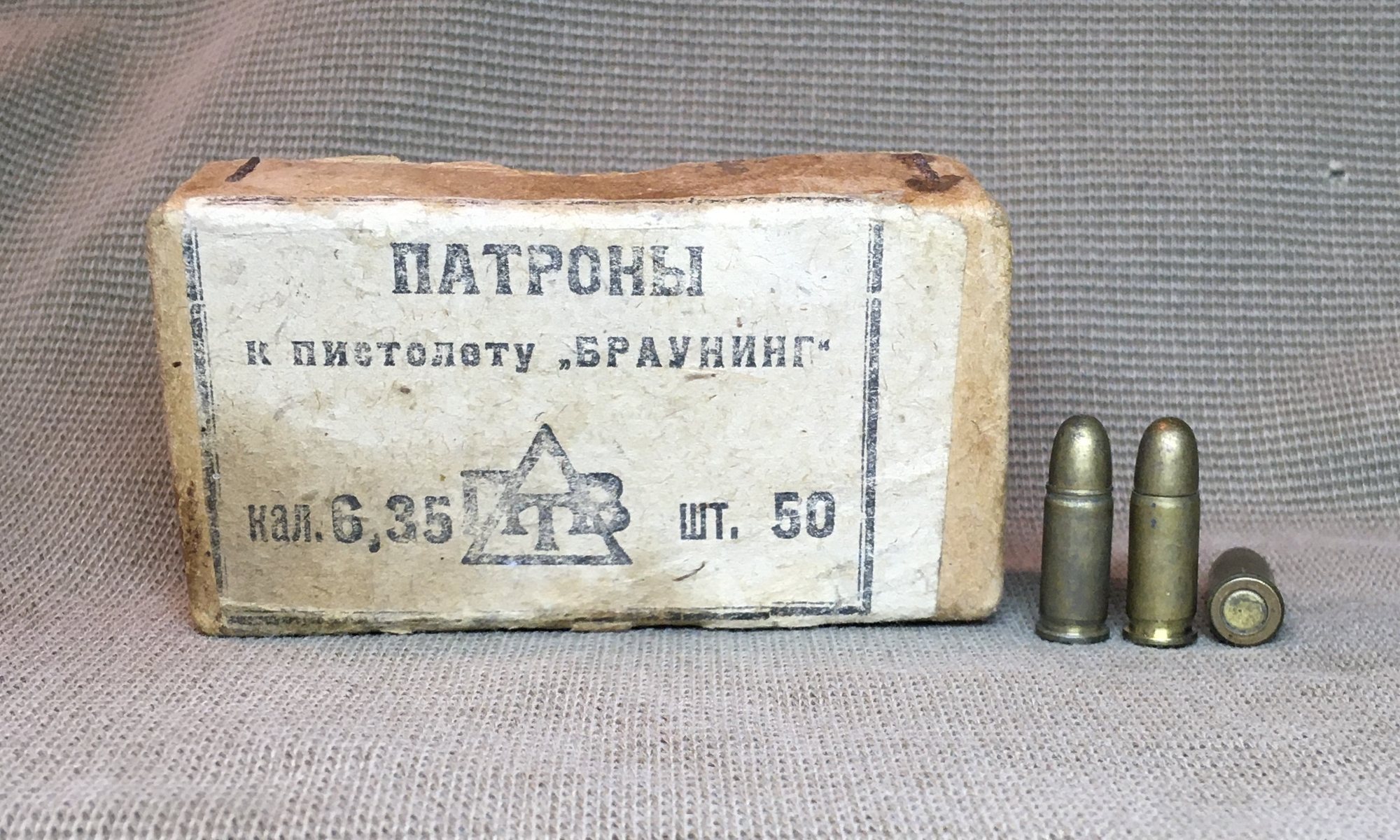 Soviet paper packet of 50 6.35 mm cartridges with three rounds beside it