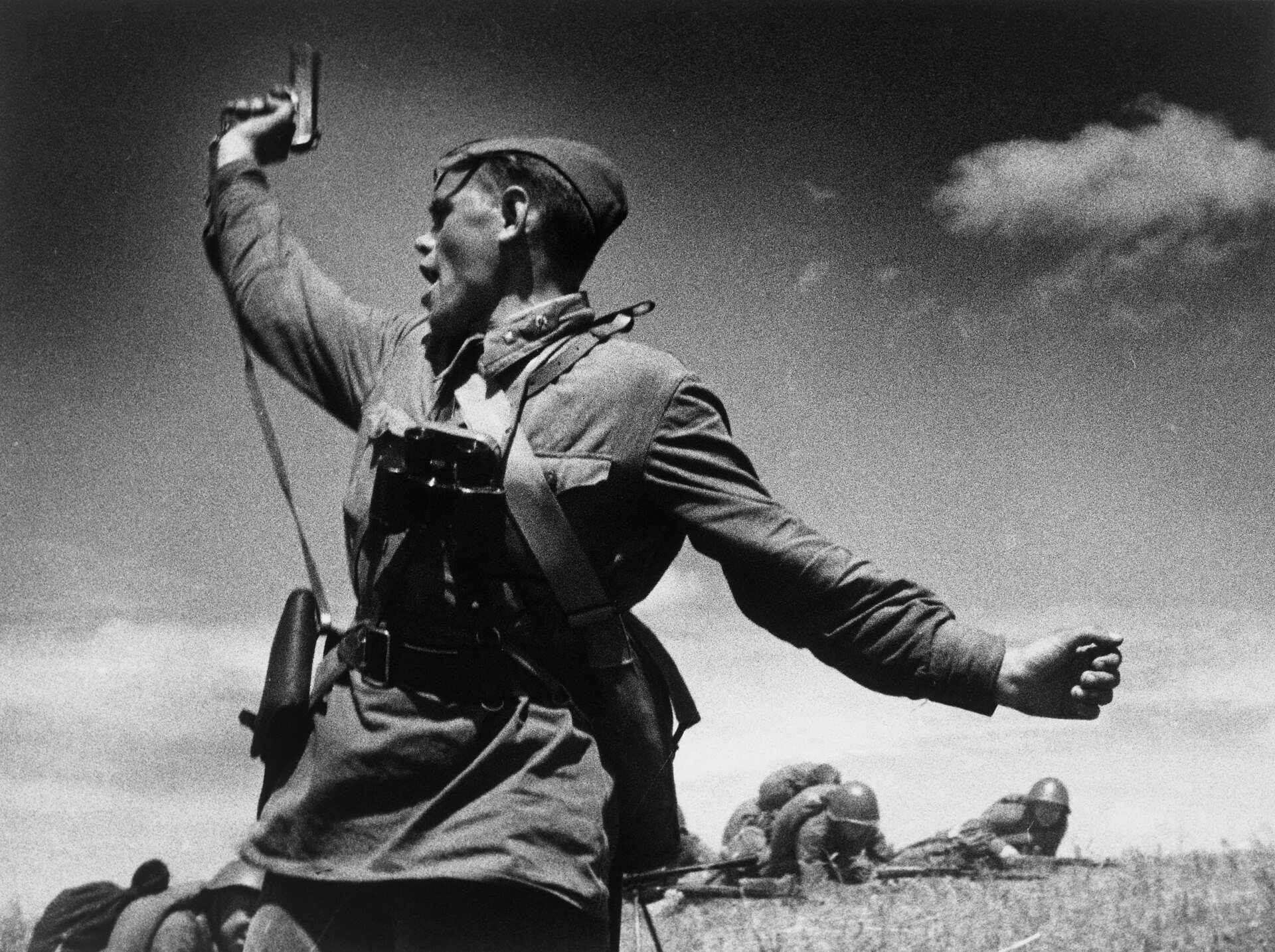 Soviet officer holding up a Tokarev TT pistol to lead soldiers forward in 1942