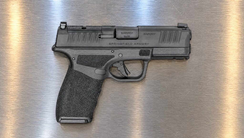Black Springfield Hellcat Pro pistol lying on a stainless steel kitchen counter at night