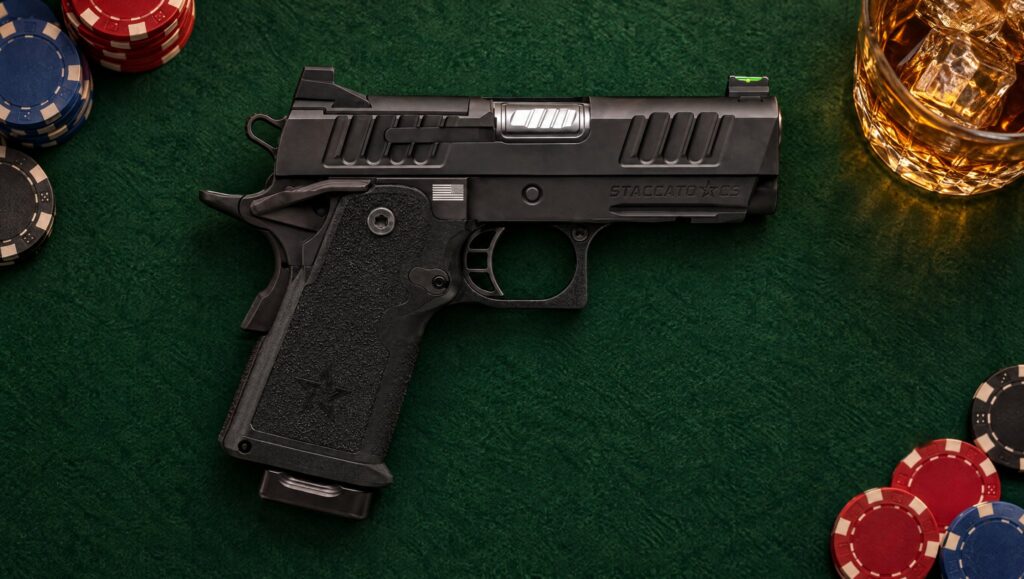 Black Staccato CS compact 2011 pistol lying on green card table felt beside poker chips and a whiskey glass