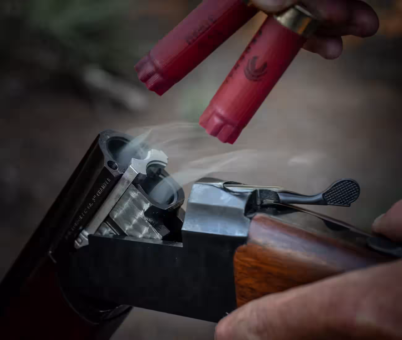 Stoeger Condor over-under shotgun opened after firing, with two smoking spent hulls being lifted out of the chambers by hand, Stoeger photo