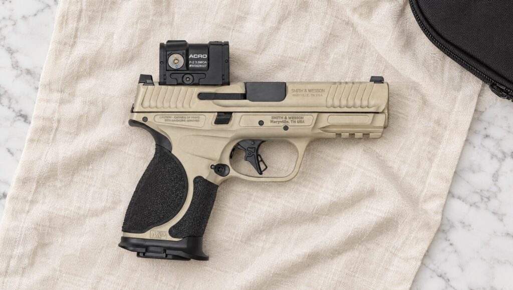 Smith & Wesson Spec Series VI M&P9 M2.0 Metal Compact in Champagne Cerakote with Aimpoint ACRO P-2 lying flat on cream linen
