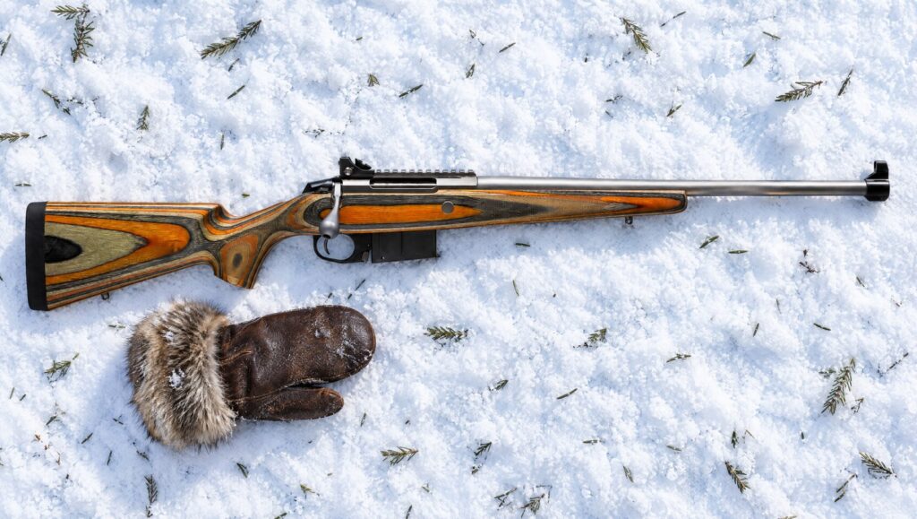 Tikka T3x Arctic with orange laminate stock, stainless barrel, open sights and Picatinny rail lying flat on packed snow