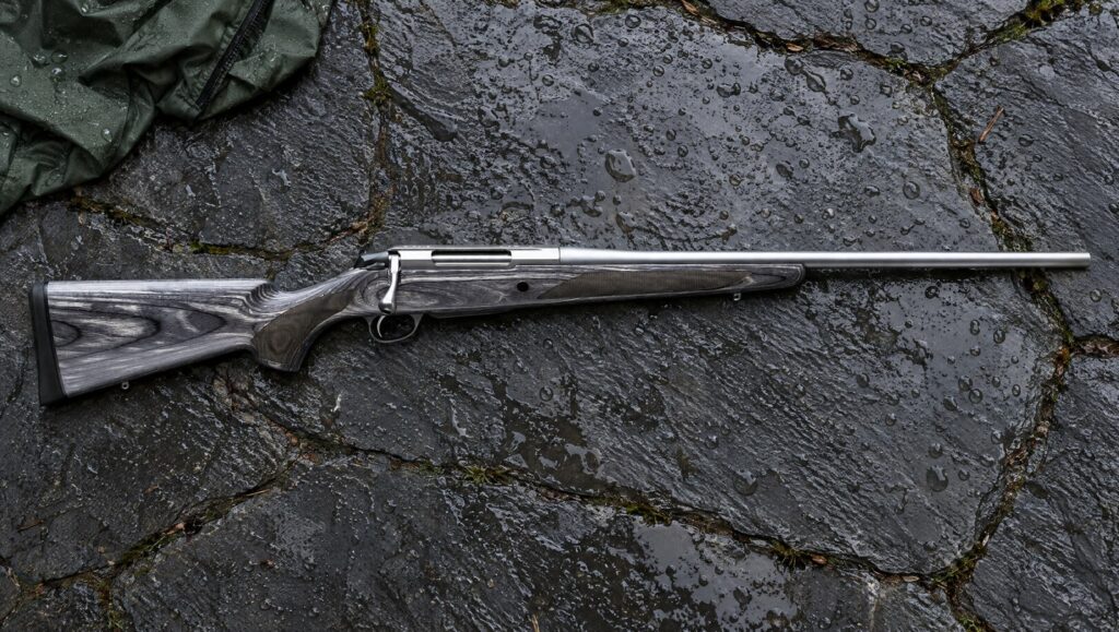 Tikka T3x Laminated Stainless with gray laminate stock and stainless barreled action lying flat on wet slate