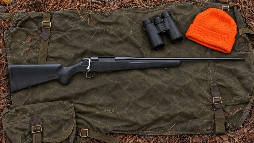 Tikka T3x Lite bolt-action rifle with black synthetic stock and blued barrel lying flat on a waxed canvas hunting pack