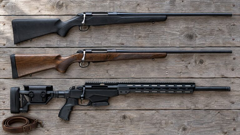 Tikka T3x models compared: a black synthetic T3x Lite, a walnut T3x Hunter and a T3x TAC A1 chassis rifle lying flat on barn wood