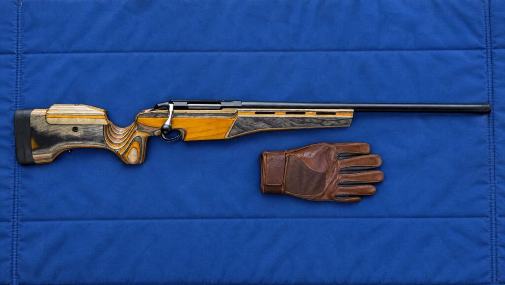 Tikka T3x Sporter target rifle with orange laminate stock and adjustable cheekpiece lying flat on a blue shooting mat