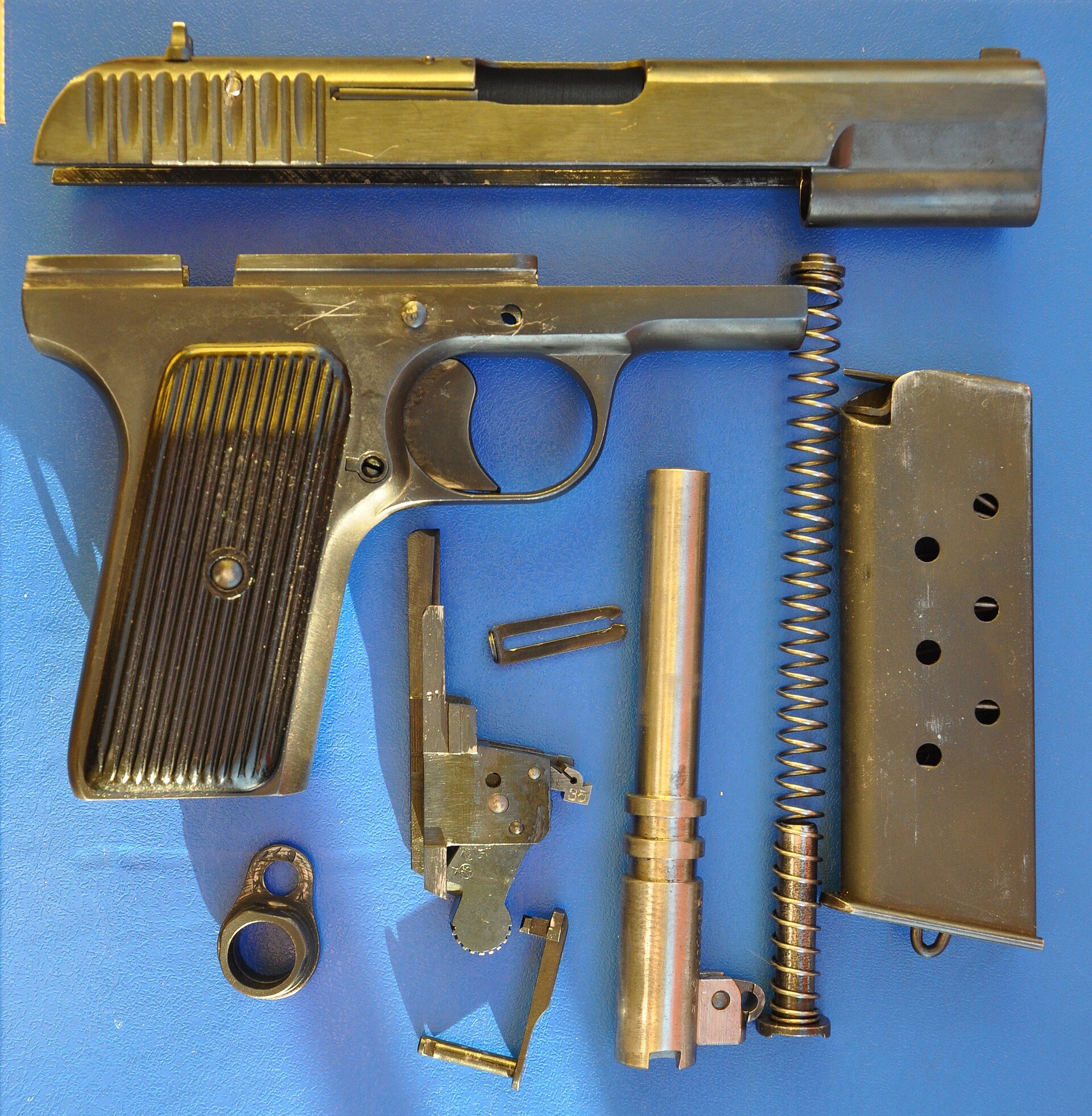 Field-stripped Tokarev TT pistol with its barrel, slide, recoil spring and magazine laid out
