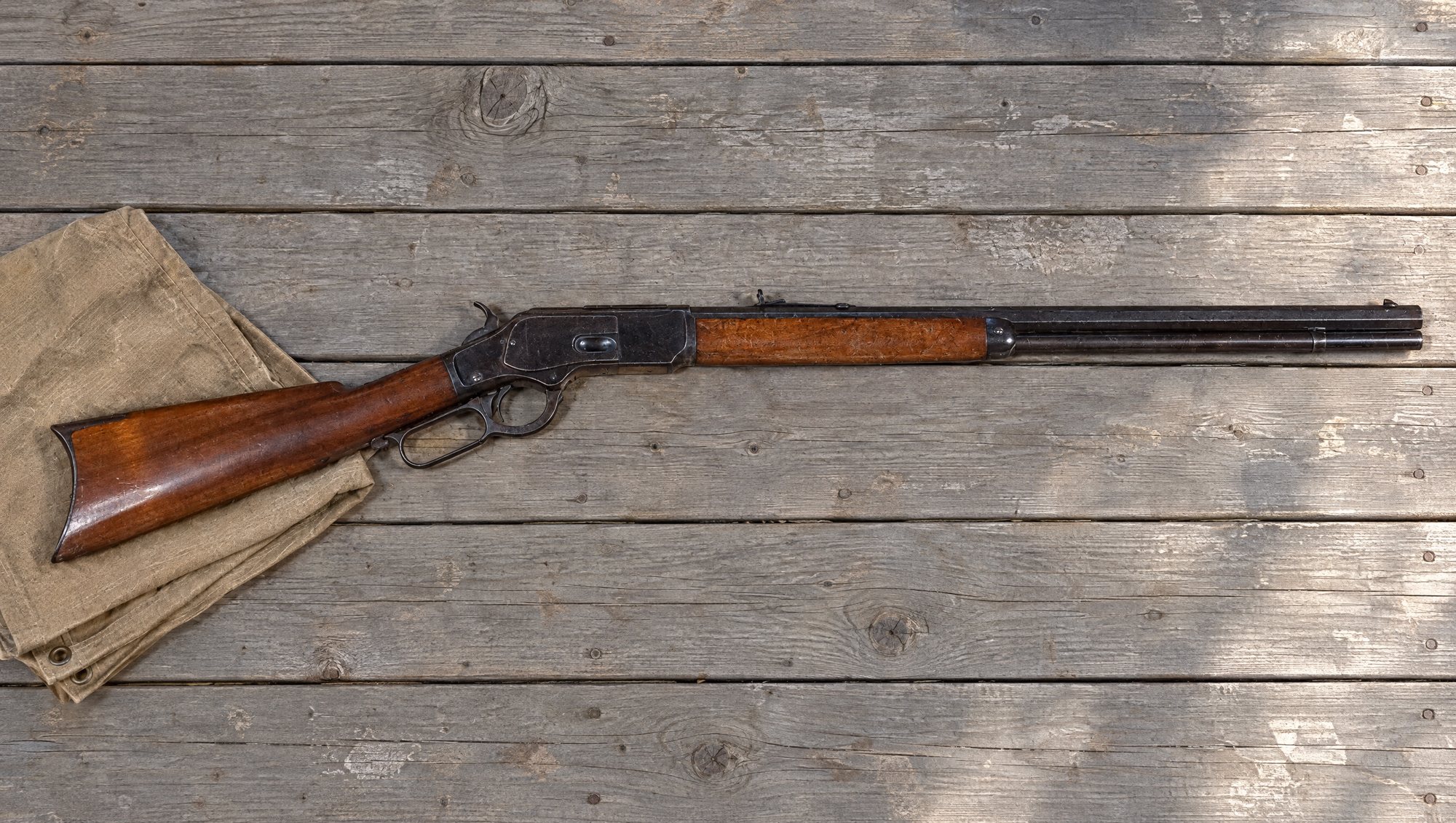 Winchester Model 1873 lever-action rifle in .44 lying on gray porch boards