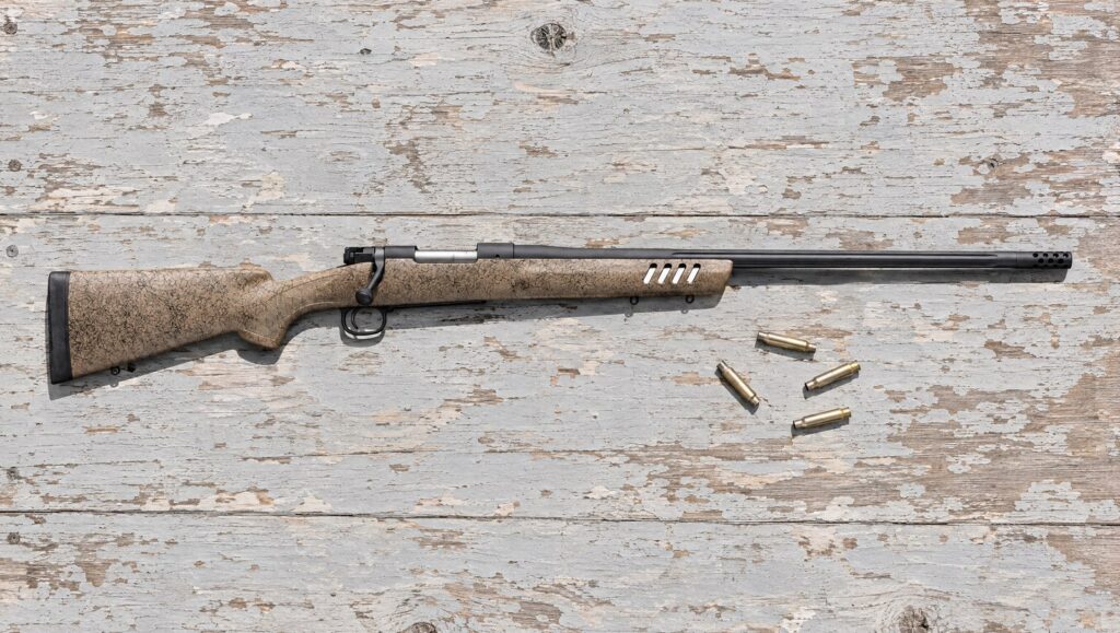 Winchester Model 70 Long Range MB with tan and black web stock, vented fore-end and fluted barrel lying flat on a plywood bench