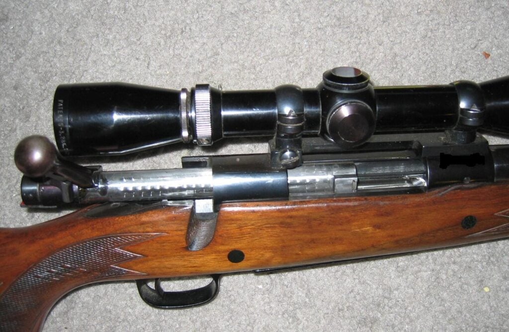 Winchester Model 70 with the bolt open and the serial number blacked out on the right side of the receiver ahead of the ejection port