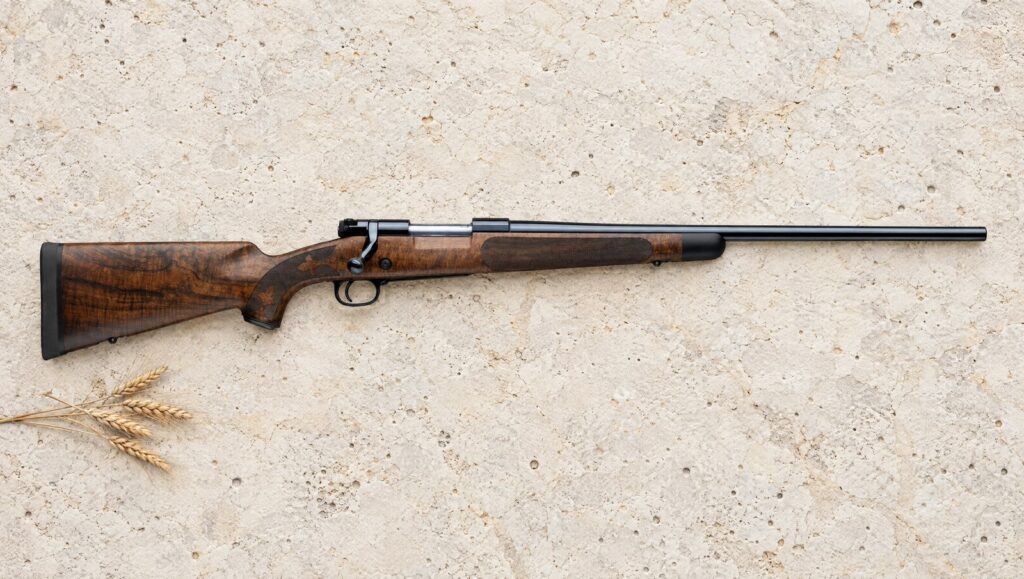 Winchester Model 70 Super Grade AAA Claro with dark streaked Claro walnut stock lying flat on pale limestone