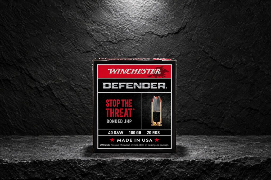 Winchester Defender S40SWPDB1 40 S&W 180 grain bonded JHP box on a slate ledge under a spotlight