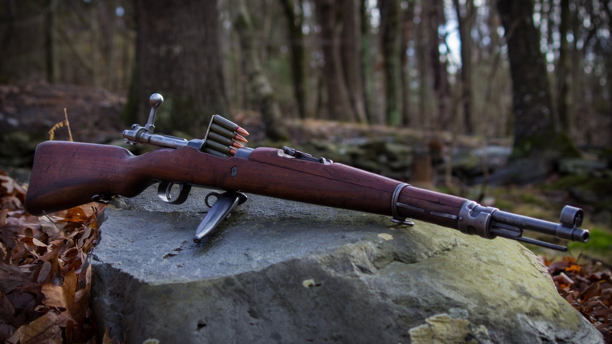 Yugoslav M24/47 Mauser rifle on a mossy rock with a stripper clip of 8mm Mauser surplus ammo in the open action